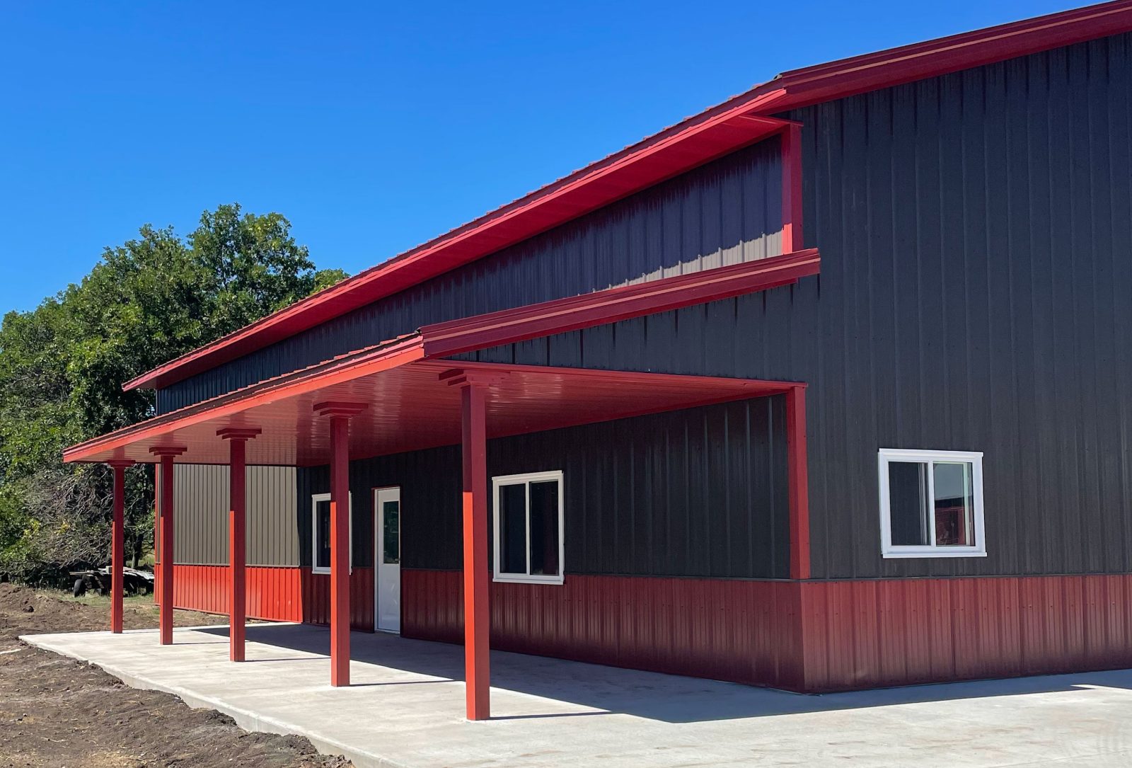Residential and hobby post-frame building with red trim and covered porch